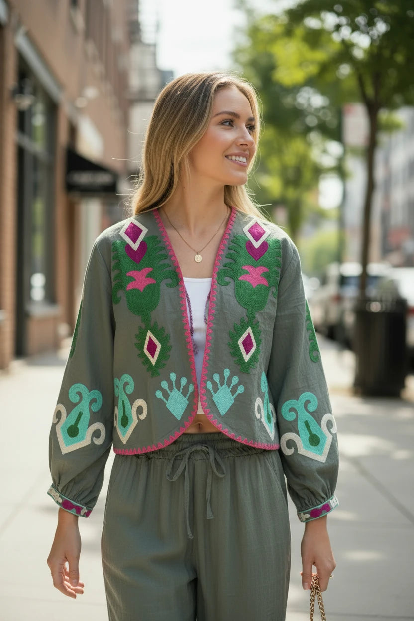 Chaqueta corta verde oliva de Iciar y Candela by Creasur S.L. con bordados florales y geométricos en fucsia, verde y turquesa. Mangas abullonadas y escote en V.